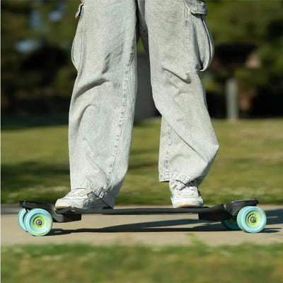 Person riding a skateboard with green wheels on a grassy area